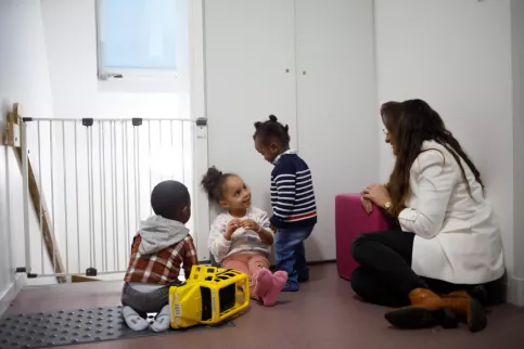 Trois enfants sont en train de jouer avec la directrice des dispositifs. 