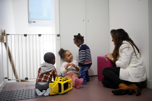Trois enfants sont en train de jouer avec la directrice des dispositifs.
